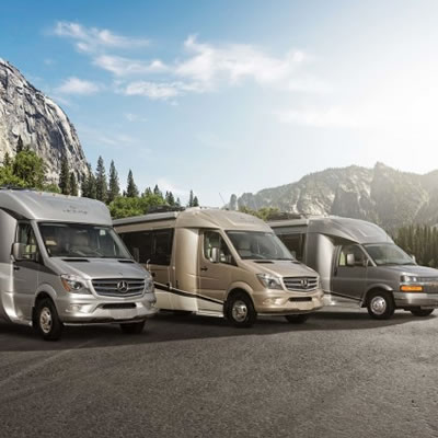 A line-up of Leisure Travel Vans, set against a backdrop of mountains. 