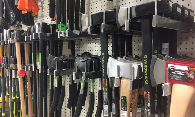 Rows and rows of axes hang for sale at a hardware store display.