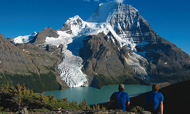 two men sitting below a mountain trail