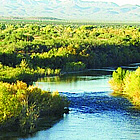 people riding horses through a river in a scenic area in Fort McDowell, AZ