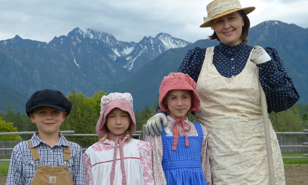 A mother and three kids dressed in costume with the mountains in the background.