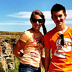 boy and a girl standing on a cliff overlooking the scenery