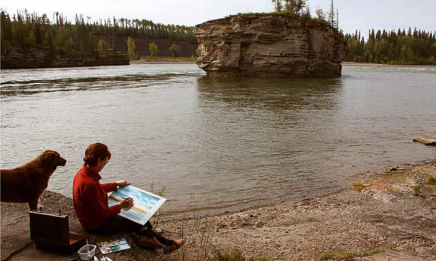 dog and lady sitting on a beach in Hudson's Hope, BC