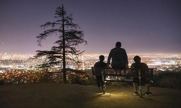 people sitting on a hill overlooking the city of LA at night