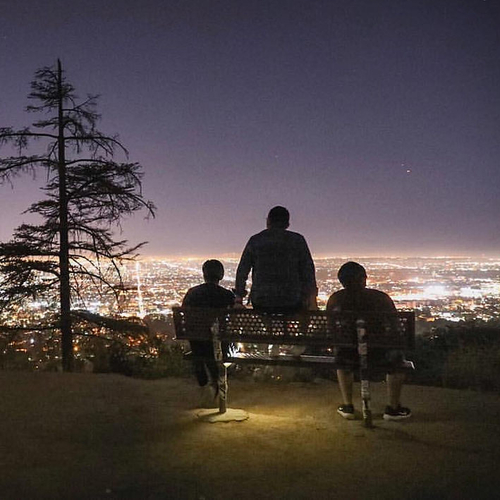 people sitting on a hill overlooking the city of LA at night