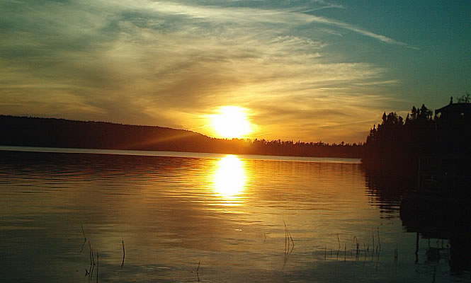 Lake with trees and sunset in the background