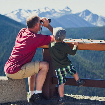 A father and sun looking through binoculars at a lookout at Manning Park.