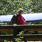 person carrying a surfboard over a bridge