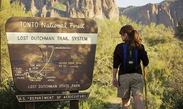 lady at a trail head sign about to go hiking