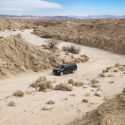 A four-wheel-drive vehicle is parked in a dry wash near the Arroyo Tapiado mud caves.