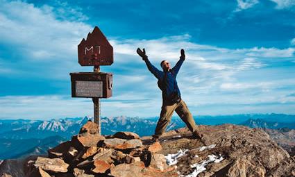 Man standing on a mountain peak with his arms raised