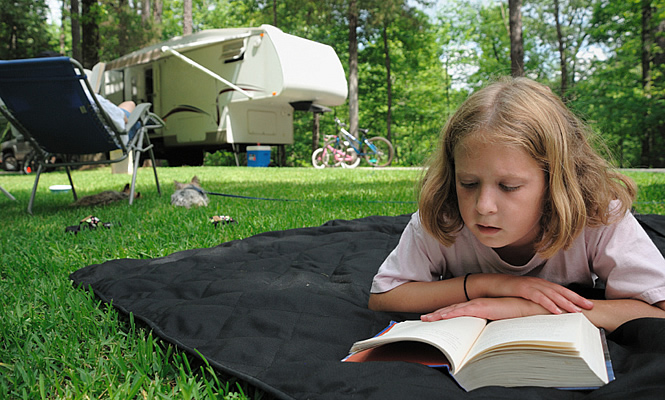 kid reading beside an RV