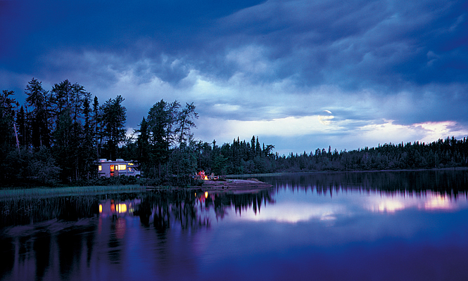 RV parked by a lake and forest