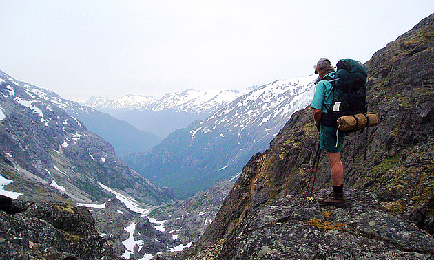 man standing on a rocky ledge overlooking a hiking trail